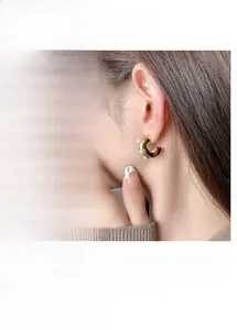 Dettaglio orecchini a perla a forma di C texture lavica in finitura oro e argento