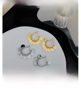 Detailed view of polished hoop earrings with hanging sequins in gold and silver finish