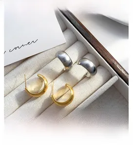 Macro shot of minimalist C-shape hoop earrings with brushed metal finish in gold and silver