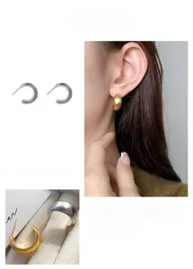 Detail view of gold and silver C-shaped stud earrings with matte brushed finish
