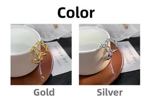 Detail of C-shaped geometric hoop earrings in gold and silver finish on a white cup