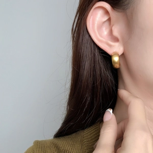 Minimalist gold-plated C-shaped earrings with a matte texture on female model
