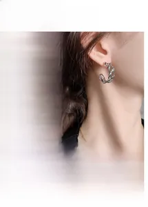 Detail of chunky C-shaped chain link hoop earrings in gold and silver finish