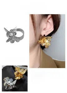 Close-up of metallic flower earrings with hammered texture and centered white pearl