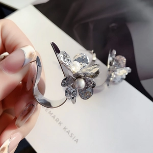 Detailed view of silver flower earrings featuring large pearls and textured petals