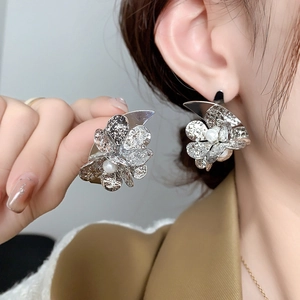 Elegant silver metallic flower stud earrings with white pearl center on model
