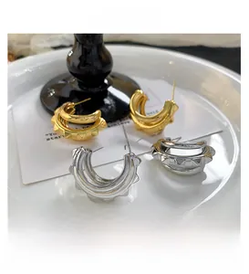 Gros plan de boucles d'oreilles en C dorées et argentées avec pointes punk sur plaque céramique