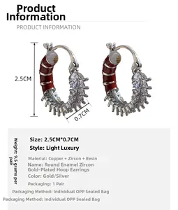 Detail view of 2.5cm caterpillar earrings with red enamel and zircon on a white background