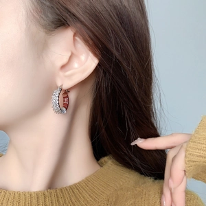Detail view of gold-plated C-shaped earrings with marquise zircon and enamel inlay