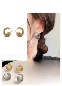 Macro shot of C-shaped earrings with micro-set cubic zirconia in gold and silver plating