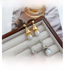 Detail of elegant gold and silver pearl bell earrings inside a velvet jewelry tray