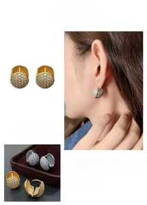 Close-up of elegant gold and silver huggie earrings set with pavé cubic zirconia