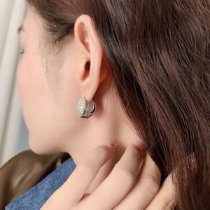 Elegant zircon paved oval hoop earrings in polished silver finish on model