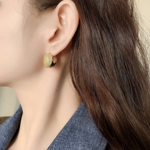 Elegant gold oval hoop earring with zircon pavé setting on a model with denim shirt
