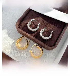 Macro detail of quilted pattern hoops in 18K gold and silver finish on velvet box