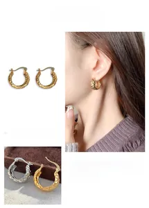Detailed view of gold and silver hoop earrings with textured diamond pattern engraving
