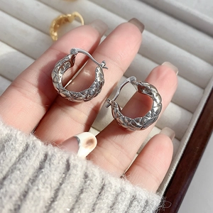 Detailed view of silver quilted hoop earrings with textured diamond pattern engraving