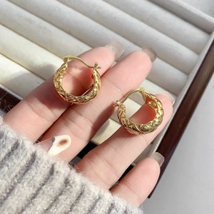 Macro shot of gold-plated hoop earrings with classic quilted pattern on jewelry box