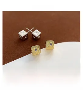 Gros plan de boucles d'oreilles carrées en or avec gemmes et dés en argent avec croix