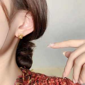 Élégantes boucles d'oreilles carrées dorées avec zircon portées sur le lobe d'oreille