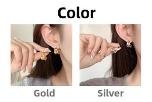 Detail view of twisted C-shape metal stud earrings in polished gold and silver finishes