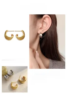 Detail of C-shaped wide hoop earrings in gold and silver finish on model