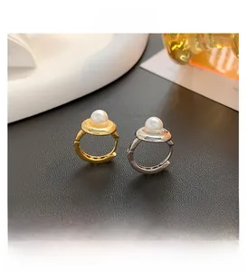 Close-up of elegant gold and silver hoop earrings featuring white pearl Saturn accents