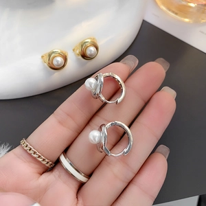 Close-up of minimalist gold and silver hoop earrings with round white pearls