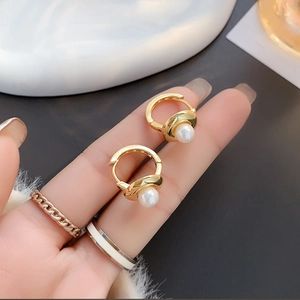 Detailed macro shot of gold hoop earrings featuring elegant white pearls and smooth finish