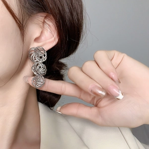 Three-tier woven silver spiral knot drop earrings worn by a model in profile