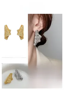 Detailed view of gold and silver irregular textured earrings with modern crumpled metal finish