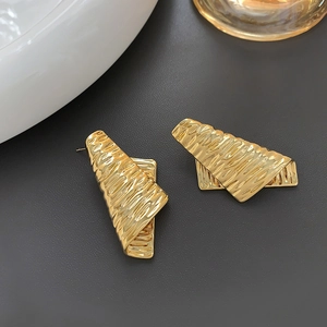 Irregular wrinkled gold earrings with hammered geometric texture on dark background