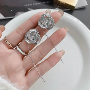Close-up of silver-plated rose earrings featuring long chain tassels and metallic shine