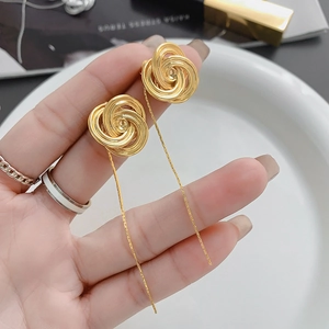 Macro shot of 24K gold-plated floral stud earrings with elegant long chain tassels