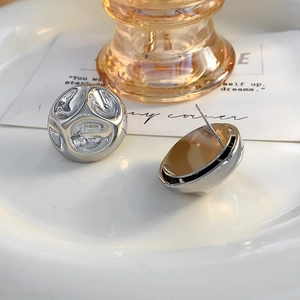 Gros plan de boucles d'oreilles argentées à texture de cratère irrégulière et fini poli