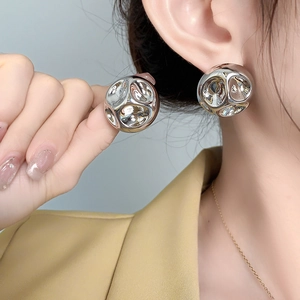 Gros plan d'un mannequin portant des boucles d'oreilles sphériques argentées texturées