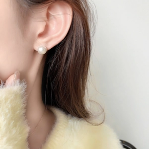 Détail d'une boucle d'oreille perle de 8mm portée par un modèle avec dorure et pull chaud