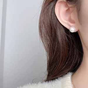 Gros plan d'une boucle d'oreille perle blanche de 10 mm à l'éclat intense sur un modèle
