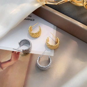 Detail of C-shaped hoop earrings with beaded texture in gold and silver finish