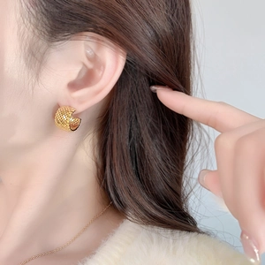 Golden C-shaped hoop earrings with intricate honeycomb mesh texture worn by model