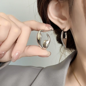 Macro shot of silver irregular geometric stud earrings with polished fluid metal texture