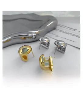 Polished geometric C-shape earrings in gold and silver finish on a decorative plate
