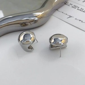 Detailed close-up of polished silver geometric stud earrings on a metallic tray
