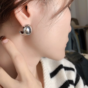 Polished silver geometric C-shape hoop earrings with sphere accent on a female model