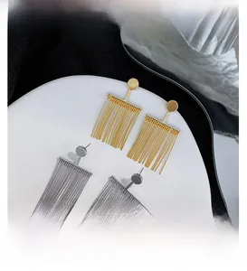Detail view of gold and silver plated tassel earrings on a sleek curved jewelry display