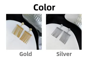 Detail view of minimalist gold and silver fringe earrings with metallic chains on a white tray