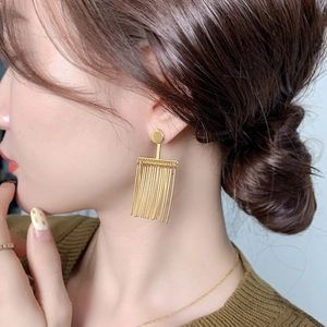 Minimalist gold tassel drop earrings worn by a model in a close-up portrait shot