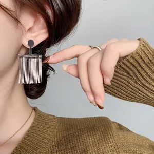 Minimalist silver long fringe tassel earrings on model in brown knit sweater