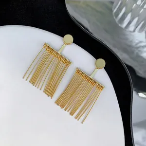 Detailed view of gold-plated geometric tassel drop earrings on a white ceramic plate