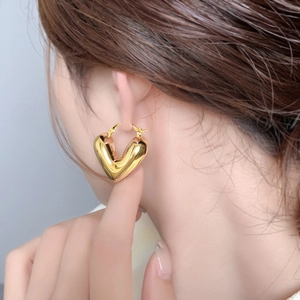 Boucles d'oreilles cœur creux plaquées or 18 carats avec finition miroir sur modèle
